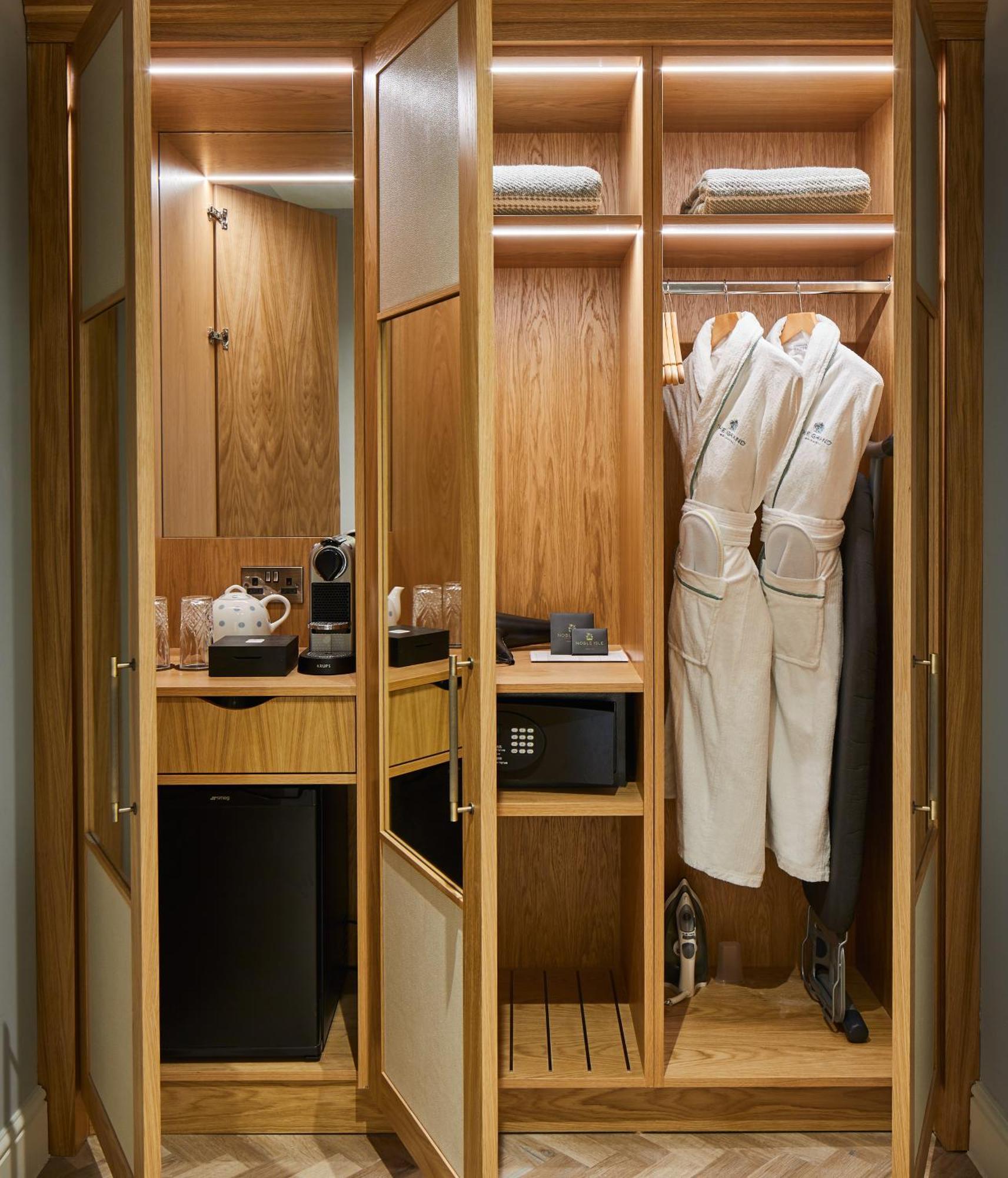 The Grand Brighton Hotell Exteriör bild The photo shows an elegantly designed closet or mini bar area featuring wooden cabinetry. Inside, there are two white bathrobes hanging on hangers, alongside various amenities. On the left side, there is a coffee maker along with mugs and other coffe