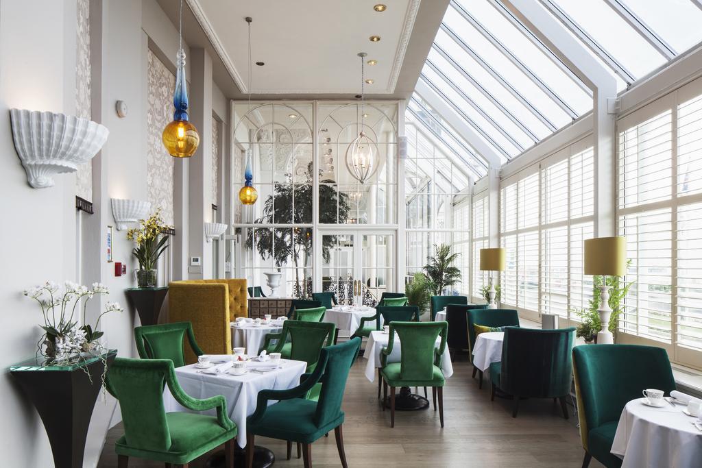 The Grand Brighton Hotell Exteriör bild The image shows a stylish restaurant interior characterized by a mix of modern and elegant design elements. The space features large windows that allow plenty of natural light, creating a bright and inviting atmosphere. 

The tables are set with whit