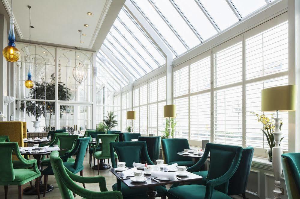 The Grand Brighton Hotell Exteriör bild The photo showcases a modern, elegant restaurant or café interior. It features large windows that allow plenty of natural light to flood the space. The walls are predominantly white, creating a bright and airy atmosphere. 

The seating consists of pl
