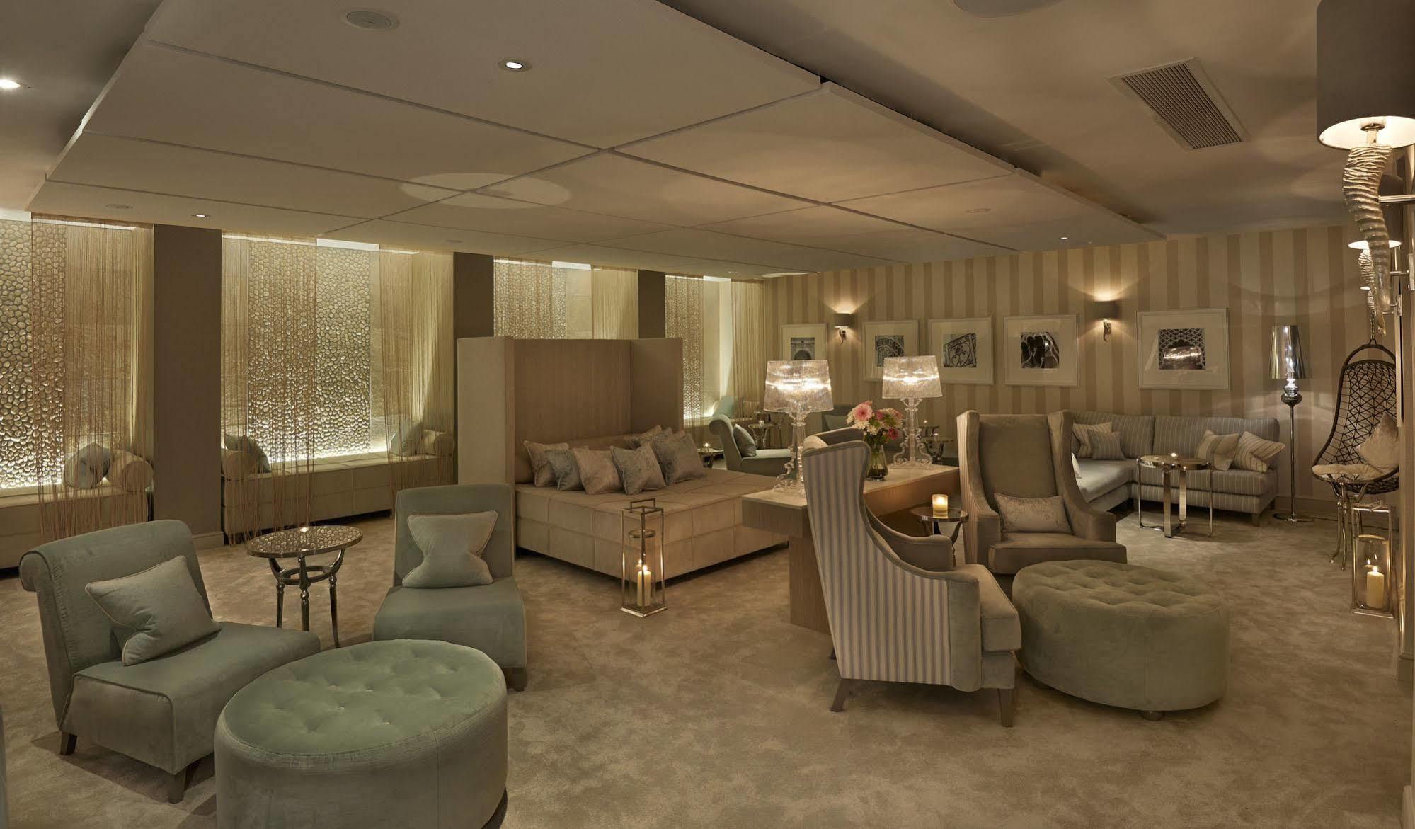 The Grand Brighton Hotell Exteriör bild The photo showcases a luxurious lounge or living area. The room features a plush, warm color palette with beige and soft green tones. There are several comfortable seating options, including a large sectional couch, armchairs, and ottomans. Elegant t