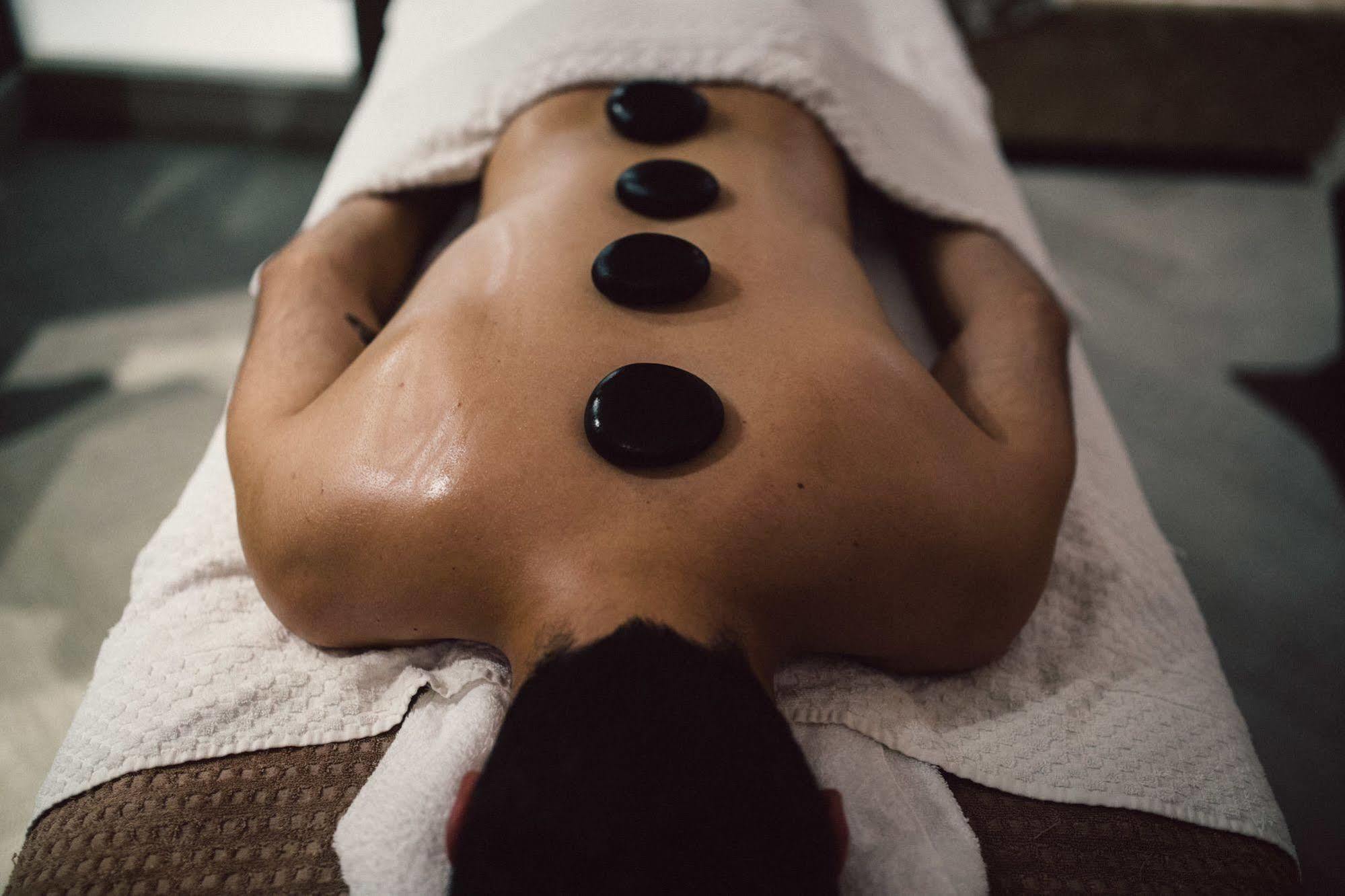 The Grand Brighton Hotell Exteriör bild The photo shows a person lying on a massage table with their back exposed. They are covered with a white towel, and there are several smooth, dark stones placed strategically along their spine. The setting appears to be a spa or wellness center, sugg