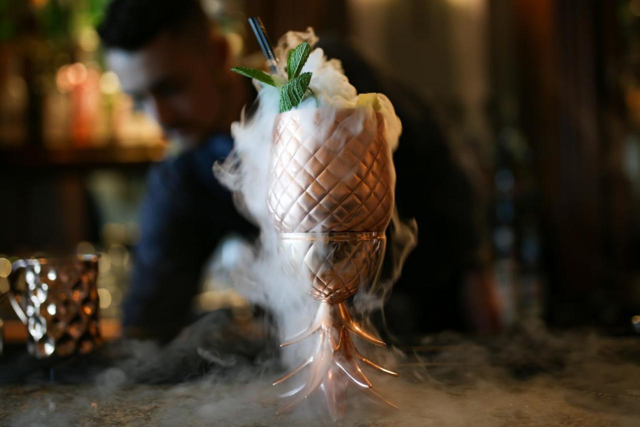 The Grand Brighton Hotell Exteriör bild The photo shows a beautifully crafted cocktail presented in a cup designed to look like a pineapple. The drink is topped with a fluffy white garnish and decorated with green mint leaves. There is a mist or smoke effect around the base of the cup, cre