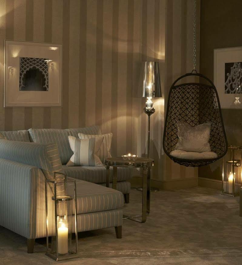 The Grand Brighton Hotell Exteriör bild The photo shows a stylish and modern living space. It features a cozy seating area with a light-colored striped sofa adorned with decorative pillows. Next to the sofa, there is a metallic side table, and a unique hanging chair made of wicker, providi